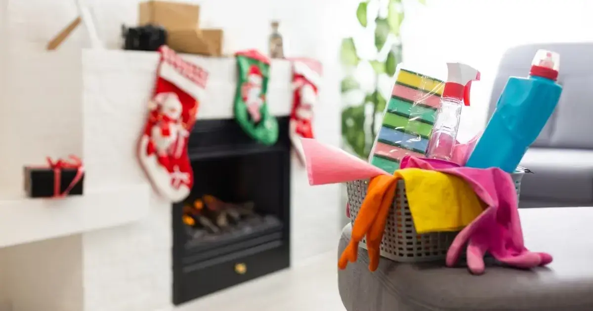 Holiday cleaning supplies near a fireplace with Christmas stockings, illustrating a Christmas cleaning checklist.