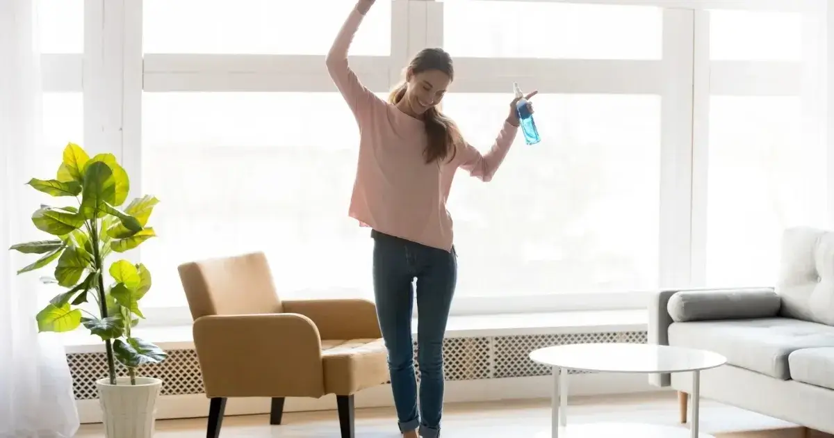 Woman in a bright living room showing how a clean house can support productivity and a more positive daily routine.