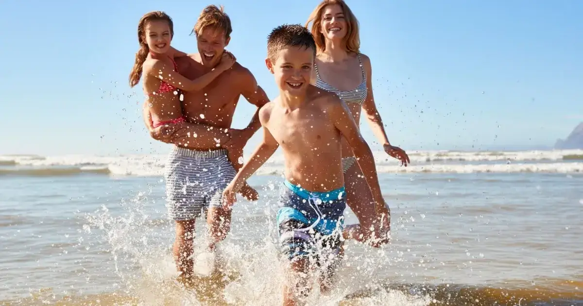 Happy family playing at the beach, representing the freedom and peace of mind that can come when you declutter before the holidays.