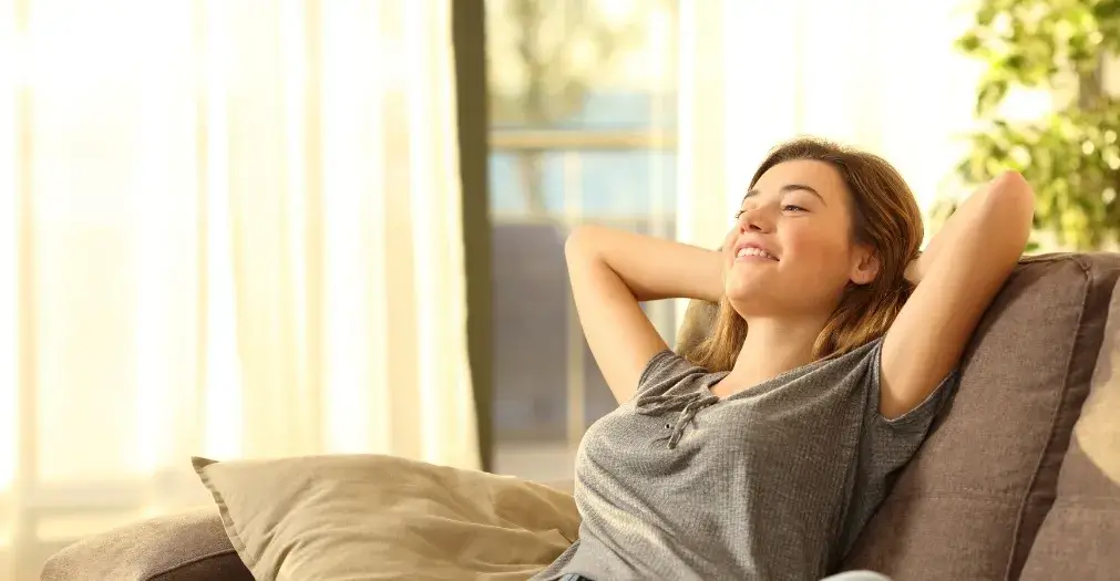 Woman relaxing comfortably on the sofa in a bright and tidy home.
