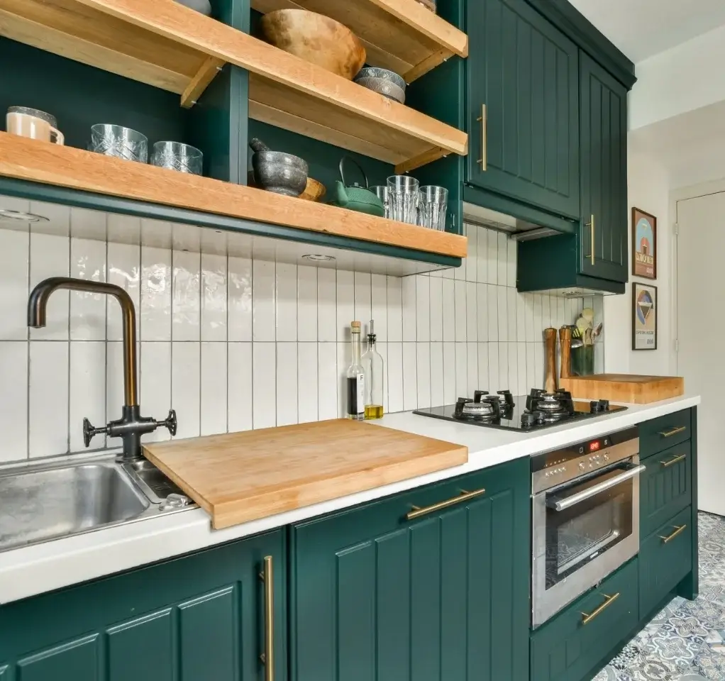 Clean residential kitchen with dark green cabinets, wooden shelves, and spotless countertops in a modern home.